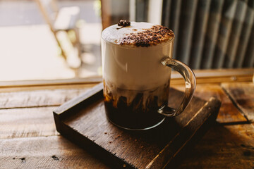 Iced coffee with milk foam and spice on top in the cafe.