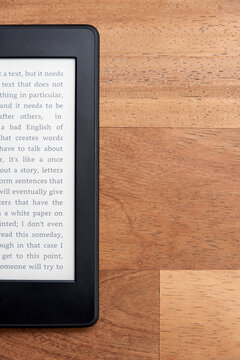 Closeup image of an electronic reader with text on the screen on a wooden desk