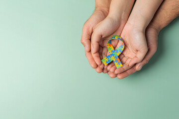 Adult and child hands holding jigsaw ribbon,World Autism Day