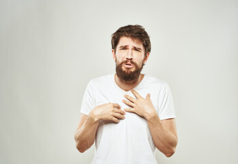 A man in a white t-shirt on a light background emotions model gesturing with hands Copy Space