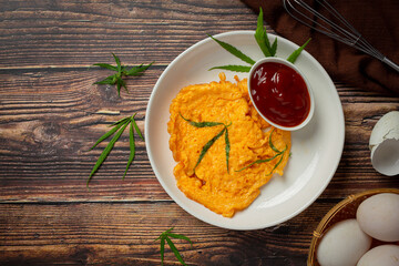 Egg omelet with marijuana leafs on old dark background