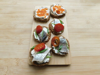 Sandwiches with red caviar and red fish on wooden planks black background.