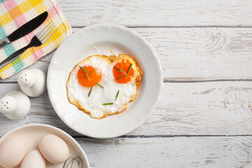 Fried eggs in a white plate on white wooden  background