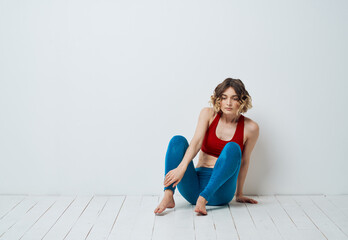 Fototapeta premium woman in blue leggings doing sports on a light floor indoors in full growth
