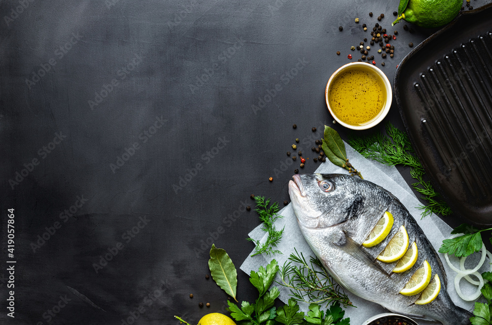 Aufkleber fresh borabo fish with grill pan and ingredients for cooking on dark background top view copy space.