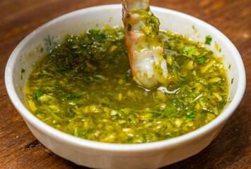 Dipping fresh prawn in a Thai hotpot sauce. Selective focus.