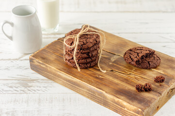 Chocolate cookies for breakfast with a glass of milk on a white wooden table.