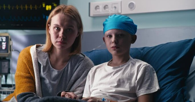 Mother and son looking at camera in hospital ward