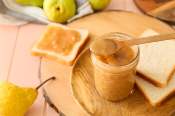 Jar of tasty pear jam with bread on wooden table