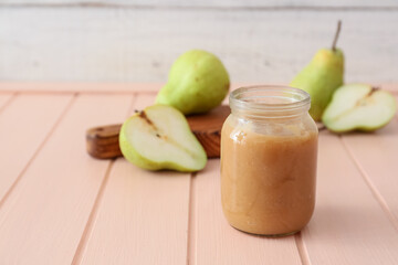 Jar of tasty pear jam on wooden table