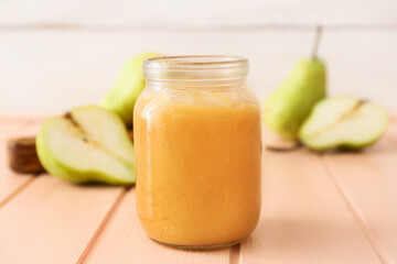 Jar of tasty pear jam on wooden table