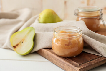 Jar of tasty pear jam on wooden table