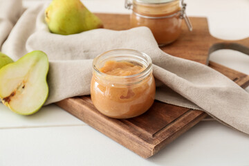 Jar of tasty pear jam on wooden table