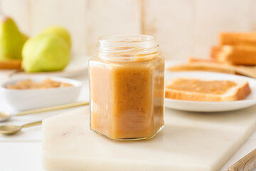 Jar of tasty pear jam on table