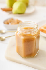 Jar of tasty pear jam on table