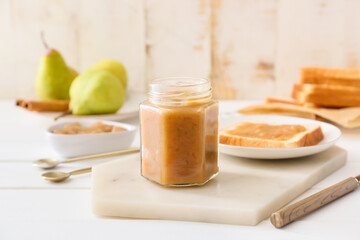 Jar of tasty pear jam on table