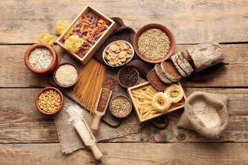 Fototapeta na wymiar Different cereals, raw pasta and bread on wooden background