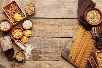 Different cereals, raw pasta and bread on wooden background