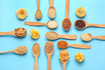 Spoons with different cereals and raw pasta on color background