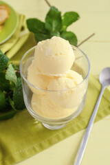 Glass with tasty banana ice-cream and mint on color wooden background