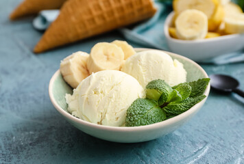 Bowl with tasty banana ice-cream and waffle cones on color background, closeup