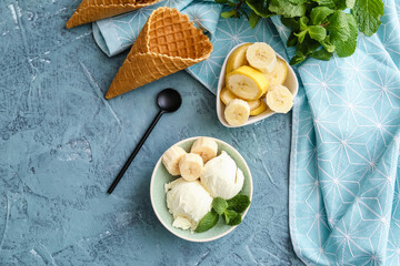 Bowl with tasty banana ice-cream and waffle cones on color background