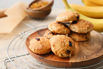 Plate with tasty banana cookies on light background