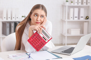 Stressed female accountant with calculator working in office