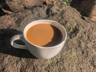 White cup of creamy coffee isolated on stone background