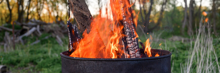 garbage incineration in rusty metal barrel. burning branches and old grass from the land plot. spring cleaning of the backyard and garden. a safe alternative to spring grass burn. banner