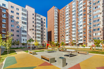 Sports grounds for adults and children playgrounds in courtyard of new modern multistory residential building in sunny summer day. Safety car-free city place for people rest