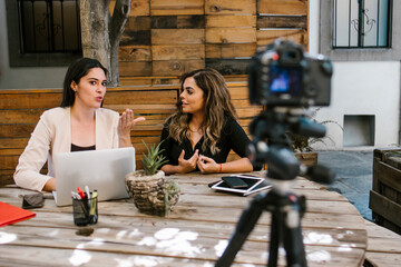 Screen of camera recording a tow hispanic women bloggers talking while making a video in a creative...