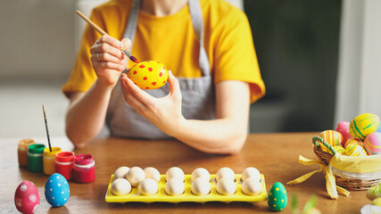 Crop woman painting eggs for Easter celebration