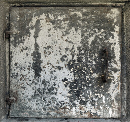 rusty and weathered metal square door of a gray box with with peeling white paint and scratches - worn steampunk background