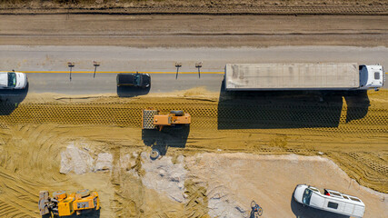 Aerial view on road roller with spikes is working at construction site, compacting base for asphalt road