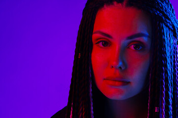 Fashion portrait of young woman with dreadlocks in neon light