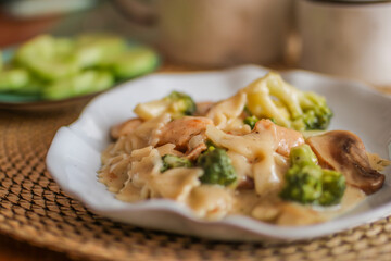 Pasta with fried mushrooms and chicken. Cheese, broccoli, champignons on the table.