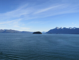 View of an island near glacier and snow covered mountains from an Alaska cruise ship.