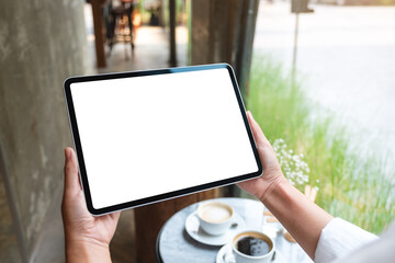 Mockup image of a woman holding digital tablet with blank white desktop screen in cafe
