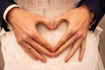 the groom hugs the bride and makes a heart out of his fingers