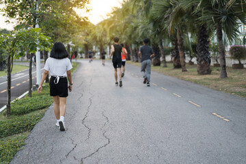 Rearview of people walking and jogging in the city park in the evening after work to relax and get a healthy life. Sports and recreation