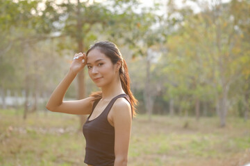 Young woman in sportswear taking a rest after jogging at the park and looking at camera.