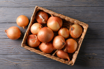 Basket with fresh onion on wooden background