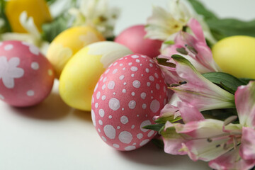 Color Easter eggs and alstroemeria flowers on white background, close up