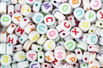 Fototapeta premium Multicolored plastic cube beads with letters scattered. Alphabet background texture.
