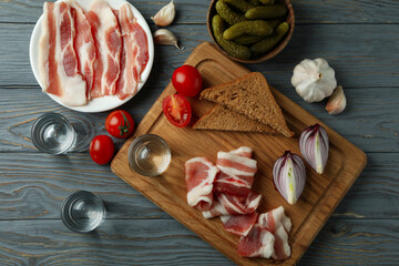 Shots of vodka and tasty snacks on gray wooden background