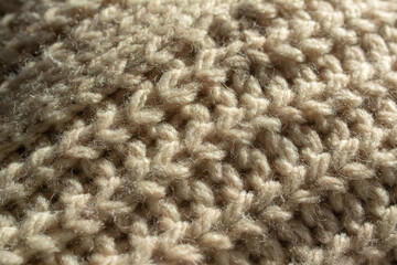 Diagonal closeup of a part of the central twist of a large knitted jumper. English knit. Beige, natural colour.