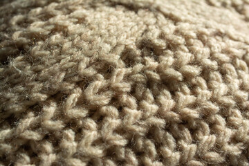 Diagonal closeup of a large knitted jumper, with central twist, English knit. Beige, natural colour.
