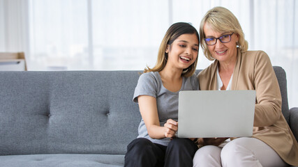 Young woman teaching mother to use laptop