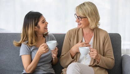 Cheerful mother and daughter drinking coffee and chatting together